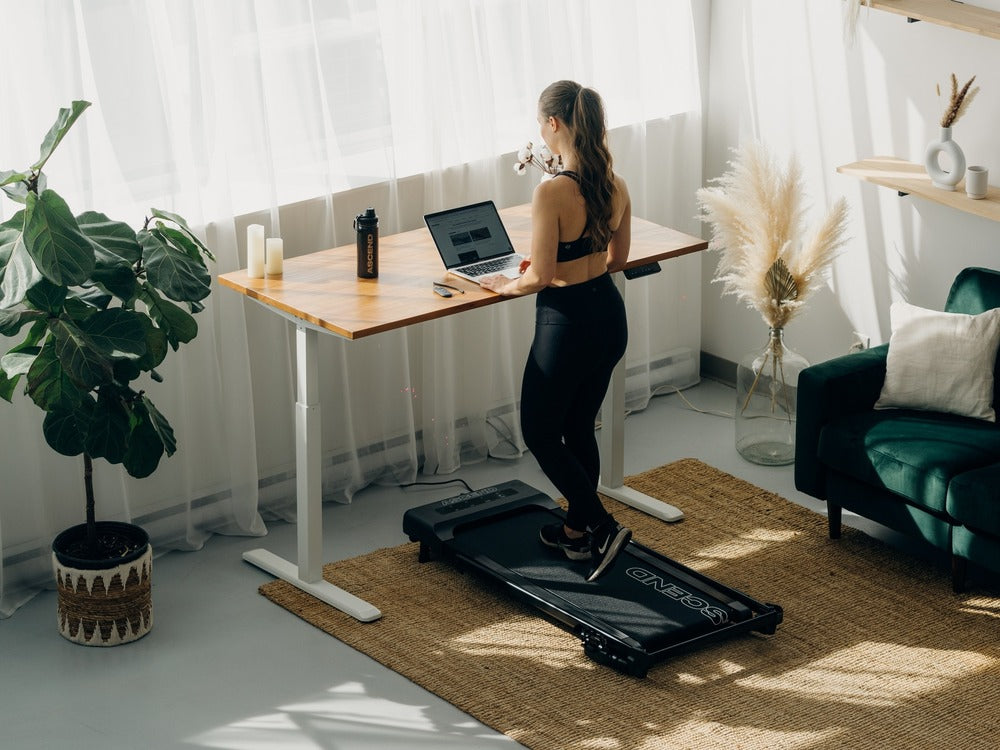 Woman using walking pad under standing desk while working